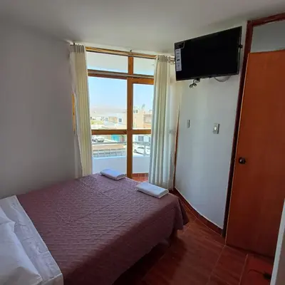 a bedroom with a bed and a tv and a window at El Capricho II Paracas in Paracas