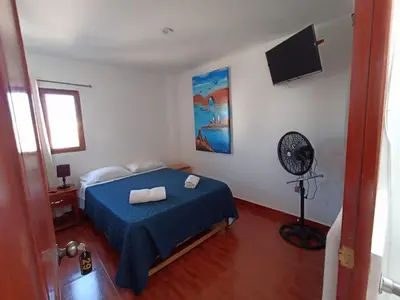 a bedroom with a blue bed and a fan at El Capricho II Paracas in Paracas
