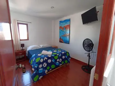 a bedroom with a bed and a fan at El Capricho II Paracas in Paracas