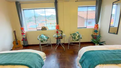 a bedroom with two beds and a table and a guitar at Apart Hotel de Alegria in Cusco