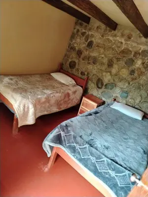 a room with two beds and a stone wall at HOSTEL SAMANA WASI CHAULLAY in Cusco