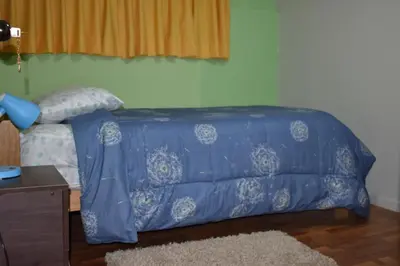 a bed with a blue comforter in a room at Saga Andina II in Cusco