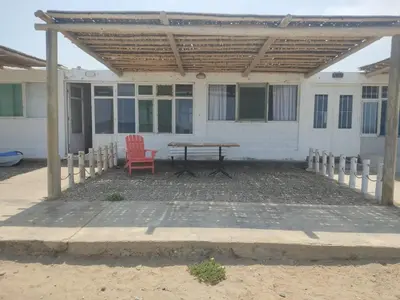 a patio with a table and a chair in front of a house at Beach House SantaElena in Pisco