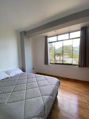 a bedroom with a large bed and a large window at Casa Hospedaje El Trebol in Oxapampa