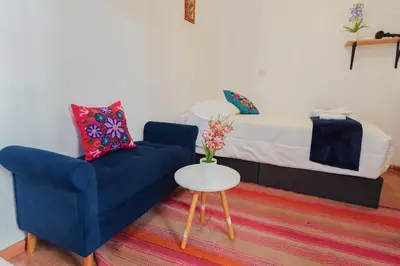 a living room with a blue chair and a bed at BEAUTIFUL, SPACIOUS & COZY HOUSE LOCATED IN THE HEART OF CUSCO in Cusco