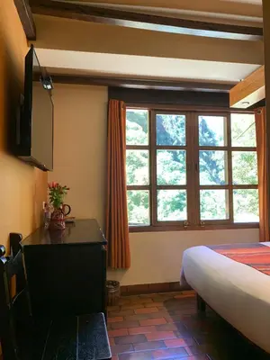 a bedroom with a bed and a desk and a window at Panorama B&B in Machu Picchu