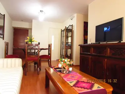 a living room with a couch and a tv and a table at Bonito Apartamento en Miraflores in Lima