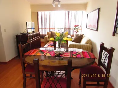 a living room with a dining room table with flowers on it at Bonito Apartamento en Miraflores in Lima