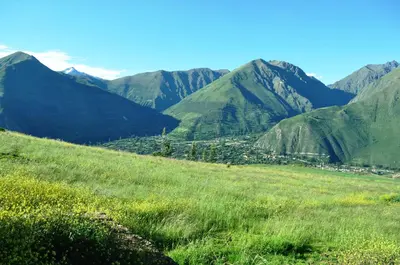 a green field with mountains in the background at Pampachayoq - Mountain retreat in Urubamba