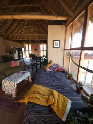 a room with two beds and a living room with windows at Pampachayoq - Mountain retreat in Urubamba