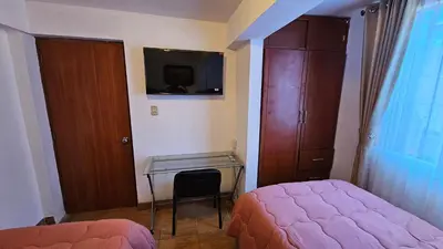 a bedroom with a bed and a desk and a tv at Casa Independiente cerca al centro historico en Primer Piso - Los Profesionales in Cusco