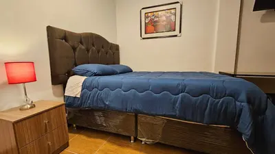 a bedroom with a bed with a blue comforter and a lamp at Casa Independiente cerca al centro historico en Primer Piso - Los Profesionales in Cusco