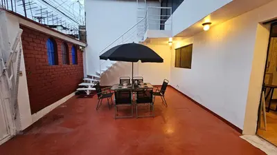 a table with chairs and an umbrella in a room at Casa Independiente cerca al centro historico en Primer Piso - Los Profesionales in Cusco