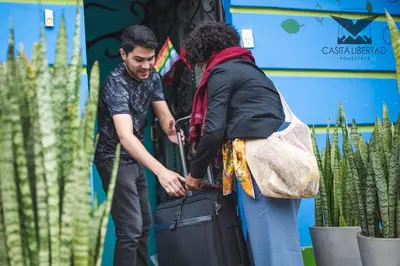 a man helping a woman with a suitcase at Casita Libertad Barranco in Lima