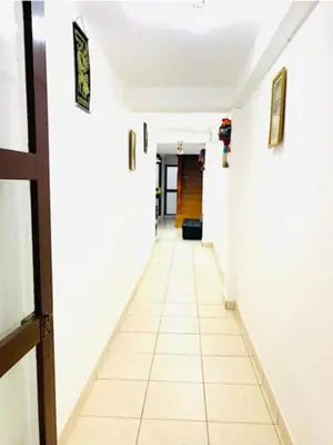 a corridor of a hallway with white walls and white tile floors at Tierra Mágica Hostal in Machu Picchu