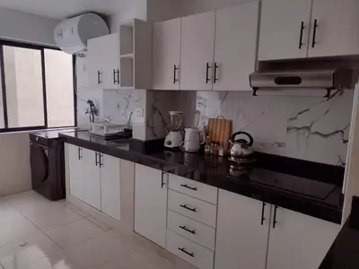 a kitchen with white cabinets and a black counter top at Bella vista al mar de Lima - Miraflores in Lima
