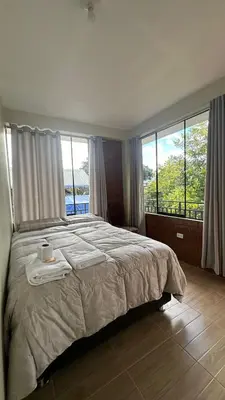 a bedroom with a large bed with large windows at La Herencia - Oxapampa in Oxapampa