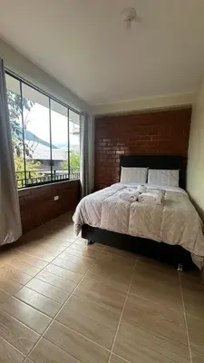 a bedroom with a bed and a large window at La Herencia - Oxapampa in Oxapampa