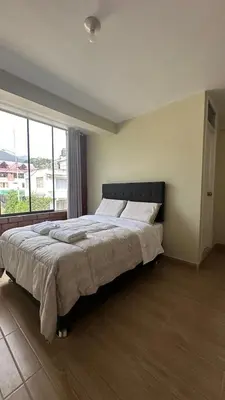 a bedroom with a large bed with a large window at La Herencia - Oxapampa in Oxapampa