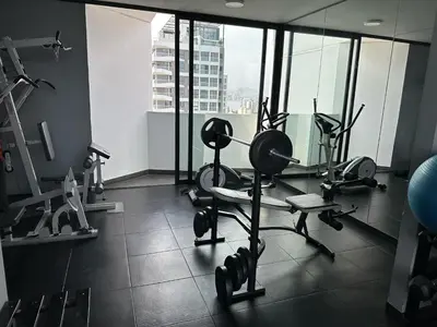 a gym with cardio equipment in a large room with windows at Departamento exclusivo a un paso de San Isidro in Lima