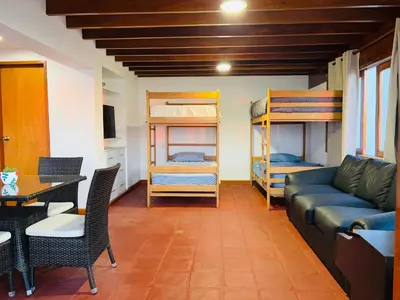 a living room with a couch and a table and bunk beds at El Templo Surf House in Punta Hermosa