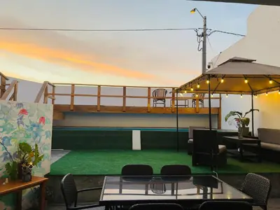 a patio with a table and chairs and an umbrella at El Templo Surf House in Punta Hermosa