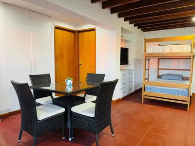 a dining room with a table and chairs and a bed at El Templo Surf House in Punta Hermosa