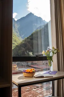 a table with a bowl of oranges and a vase of flowers at Mamasara Machupicchu in Machu Picchu