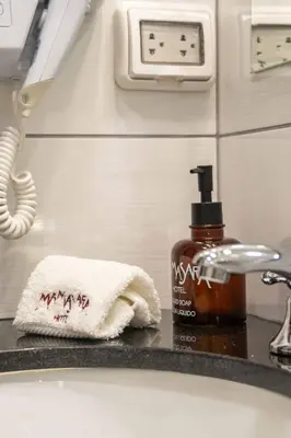 a bathroom sink with a towel and a bottle of soap at Mamasara Machupicchu in Machu Picchu