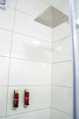 a white tiled bathroom with two fire hydrants at Mamasara Machupicchu in Machu Picchu