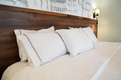 a bed with white pillows and a wooden headboard at Hotel Tierra Inka Sacred Valley in Ollantaytambo