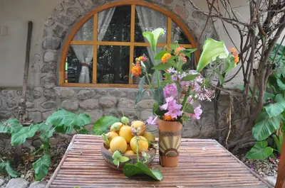 a table with a bowl of fruit and a vase of flowers at Valle Dorado Lodge in Cusco