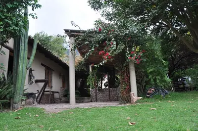 a house with a pergola with flowers on it at Valle Dorado Lodge in Cusco
