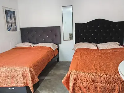 a bedroom with two beds with orange sheets and a mirror at Quinoa Backpackers Hostel in Lima