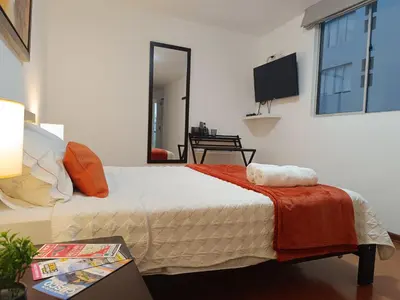 a bedroom with a bed with a television on the wall at Runawasi Apartments - José Gonzales 3BDR, near to Larcomar in Lima
