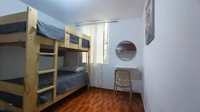 a bedroom with two bunk beds and a chair at Mini Apartamento Vista Verde in Lima