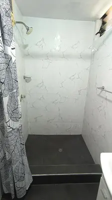a bathroom with a shower with a white tiled wall at Mini Apartamento Vista Verde in Lima