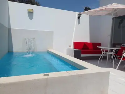 a swimming pool with a red couch and a table at Departamento en playa Chocaya. Disfruta del mar, la piscina y la tranquilidad. in Asia