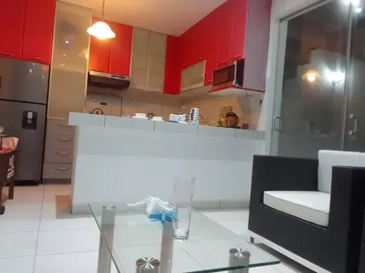 a kitchen with red cabinets and a glass table at Departamento en playa Chocaya. Disfruta del mar, la piscina y la tranquilidad. in Asia