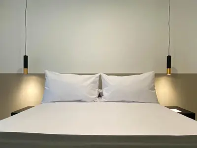 a white bed with three pillows on it at Alameda by Wynwood House in Lima