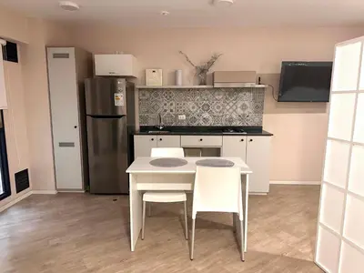 a kitchen with a table and two chairs and a refrigerator at Friendly Apartment Tamayo in Lima