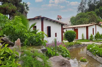 a house with a river in front of it at Los Andes - Restaurant & Bungalows in Cieneguilla