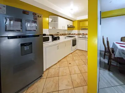 a kitchen with yellow walls and a stainless steel refrigerator at Killa Anqas - Departamento en el centro del Cusco in Cusco