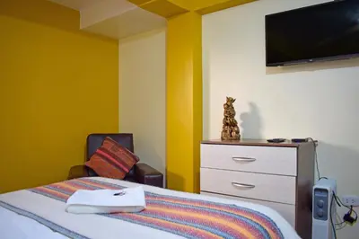 a bedroom with a bed and a tv on the wall at Killa Anqas - Departamento en el centro del Cusco in Cusco