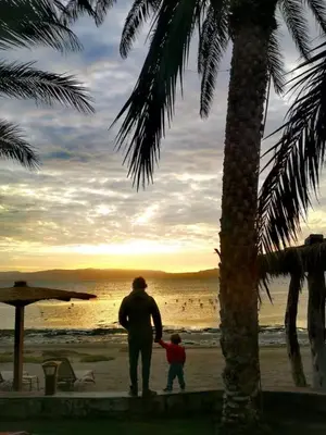 a man and a child walking on the beach at Relájate en piscina-spa, terraza BBQ y AC Paracas in Paracas