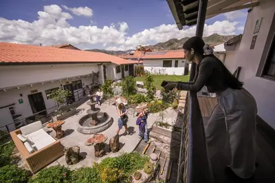 a woman standing on a balcony looking at a garden at Black Llama Hostel Cusco in Cusco
