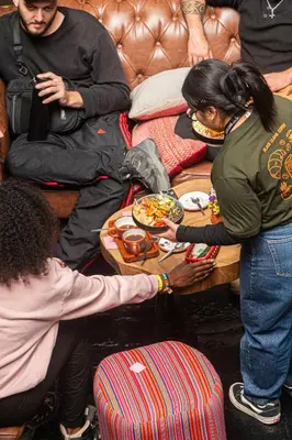 a group of people standing around a table with food on it at Black Llama Hostel Cusco in Cusco