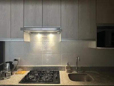 a kitchen counter with a stove and a sink at Apartamento 3 habitaciones, Santa Beatriz - Perú in Lima