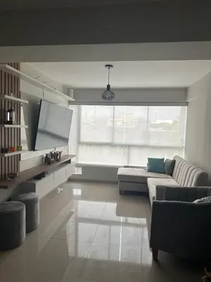 a living room with a couch and a large window at Apartamento 3 habitaciones, Santa Beatriz - Perú in Lima