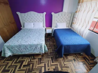 a bedroom with two beds and purple walls at SUMAQ PUNUY HOSTEL - Lima Airport in Lima